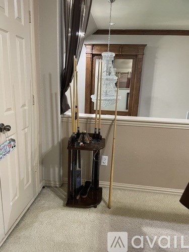 A room with a white door, a brown table with a lamp and some items on it, and a white wall.
