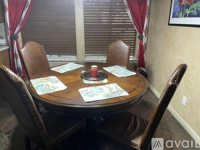 A round wooden table surrounded by chairs with a red cup on the table.