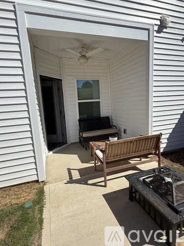 A patio with a bench, table, and a ceiling fan.