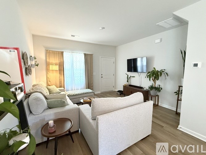 A living room with a white couch, a brown coffee table, and a flat screen TV mounted on the wall.