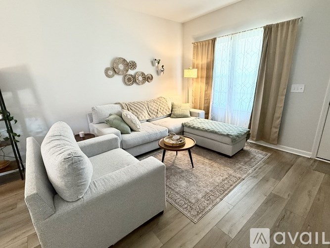 A living room with a grey couch, a small table, and a bed with a white bedspread.
