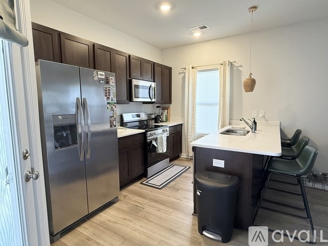 A kitchen with a refrigerator, microwave, and sink.