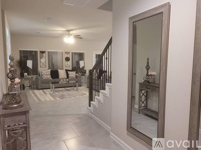 A hallway with a staircase and a mirror on the wall.