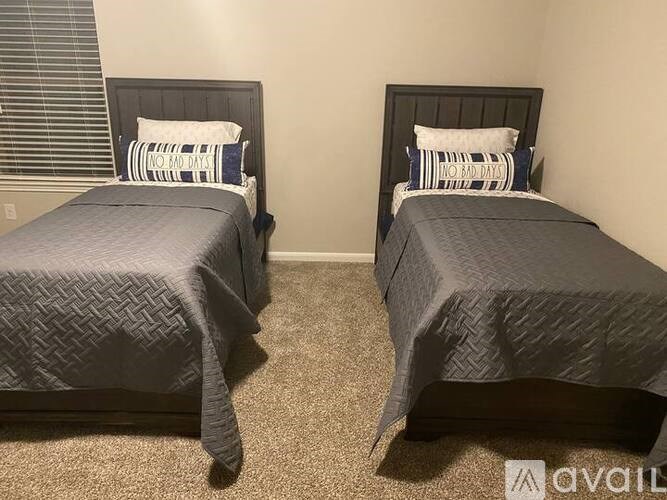 Two twin beds with grey bedspreads and pillows with the text "NO BAD DAYS" on them.