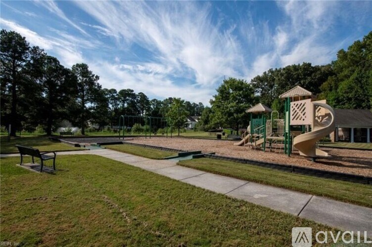 A playground with a slide and a green structure is surrounded by trees.