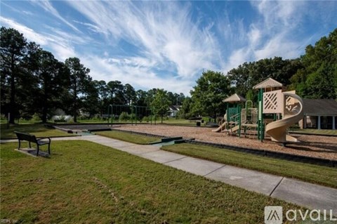 A playground with a slide and a green structure is surrounded by trees.