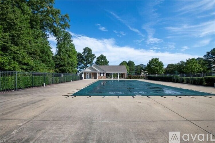 A large, empty parking lot with a building in the background and a fence surrounding the area.