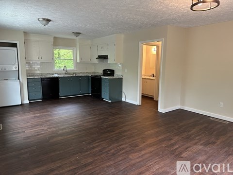 A kitchen with dark wood floors and white walls.