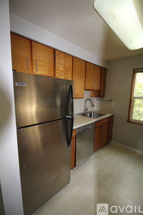 A kitchen with a stainless steel refrigerator and wooden cabinets.