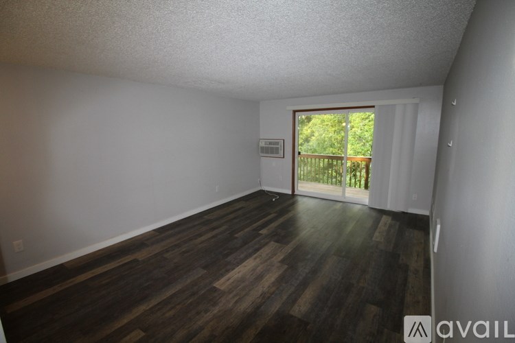 A room with wooden floors and a window leading to a balcony.