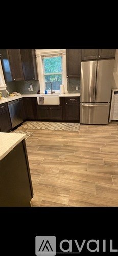 A kitchen with a refrigerator, sink, and window.