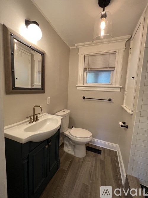 A bathroom with a sink, toilet, and mirror.
