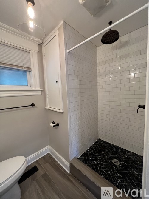 A bathroom with a toilet, a shower, and a window.