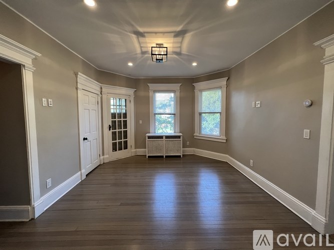 A spacious room with wooden floors and a large window.