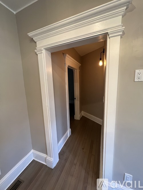 A hallway with a light on and a door at the end.