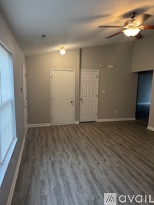 A room with a ceiling fan and two doors.