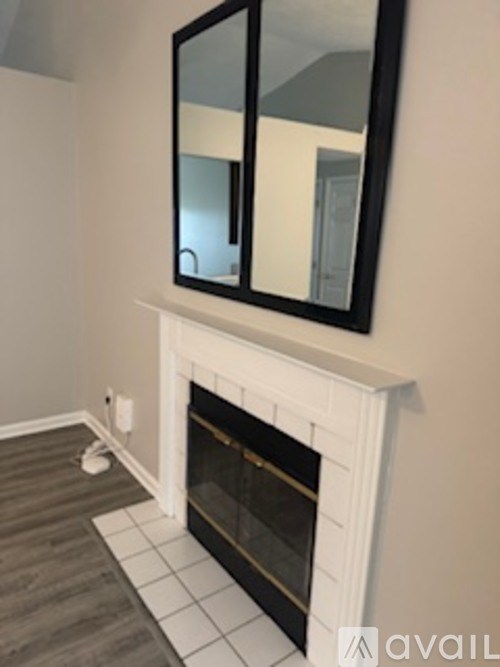 A white fireplace with a black framed mirror above it.