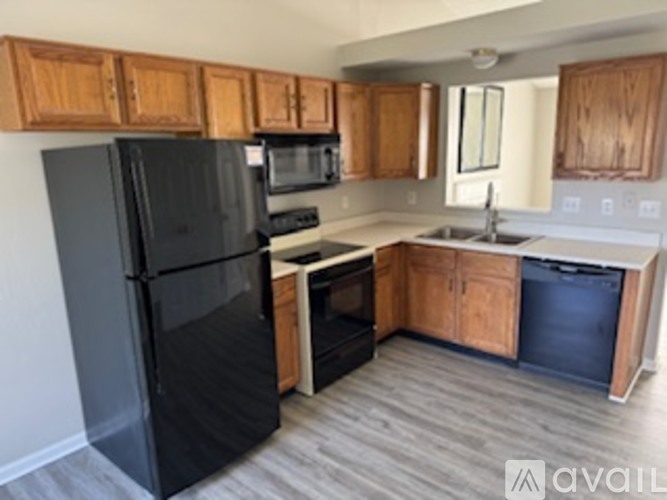 A black refrigerator is in a kitchen with wooden cabinets.