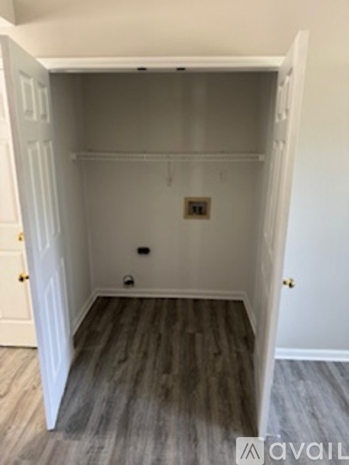 A white closet with a wooden floor and a white door.