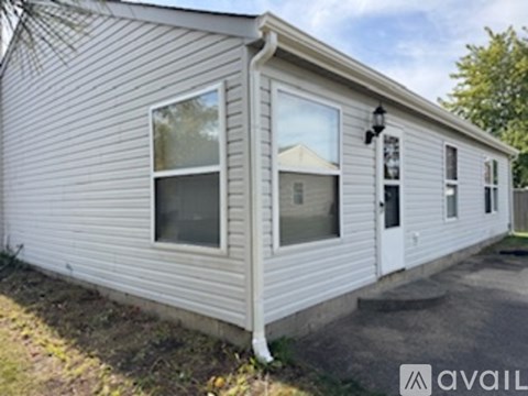 A house with a white door and windows is available for rent.