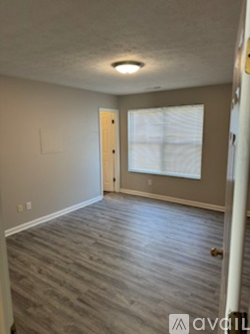 A room with a wooden floor and a door leading to another room.