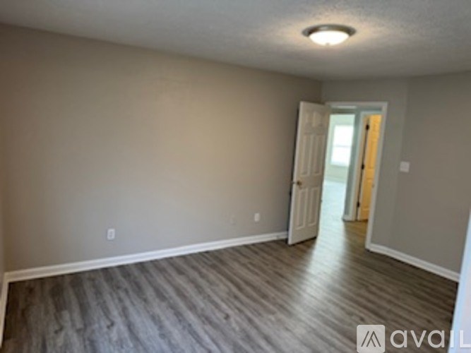 A room with wooden flooring and a doorway leading to another room.