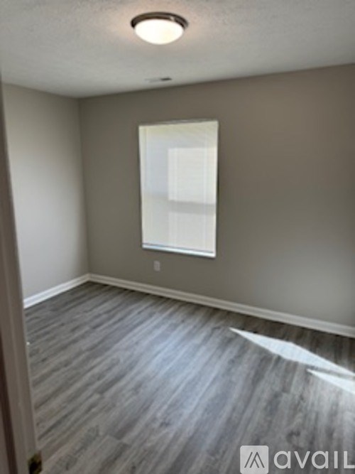 A room with a window and wooden flooring.