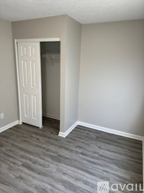 A room with a white door and a grey carpet.