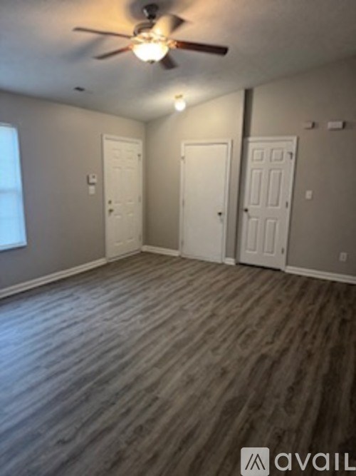 A room with a ceiling fan and wooden flooring.