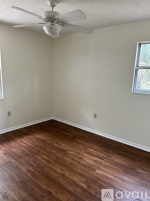 A room with a ceiling fan and wood flooring.