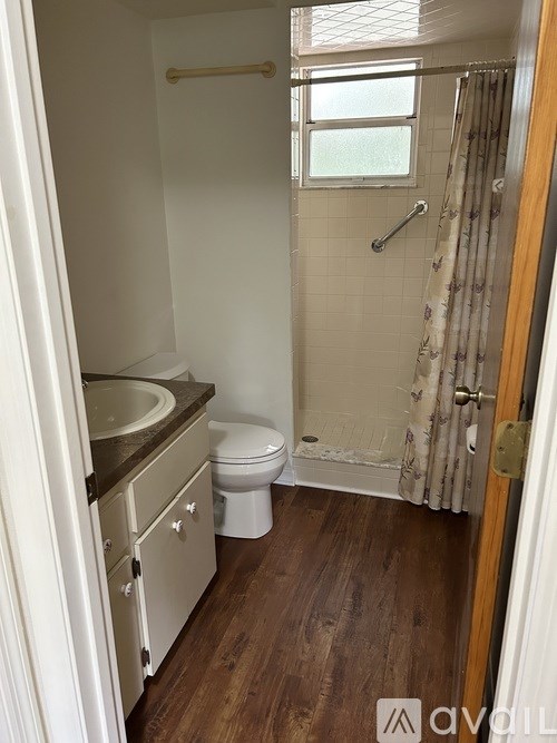 A small bathroom with a toilet, sink, and shower.