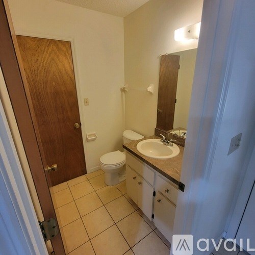 A bathroom with a toilet, sink, and mirror.