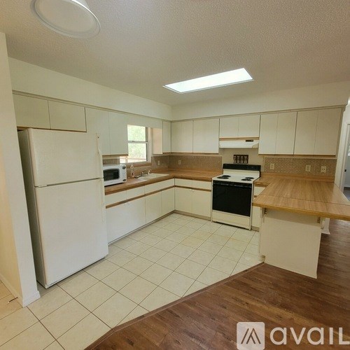 A kitchen with white appliances and wooden countertops.