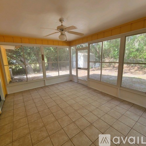 A sunroom with a ceiling fan and tiled floor.