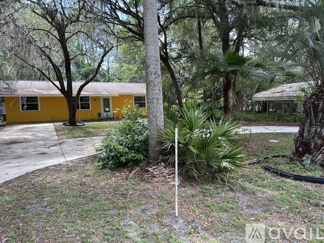 A yellow building is surrounded by greenery.