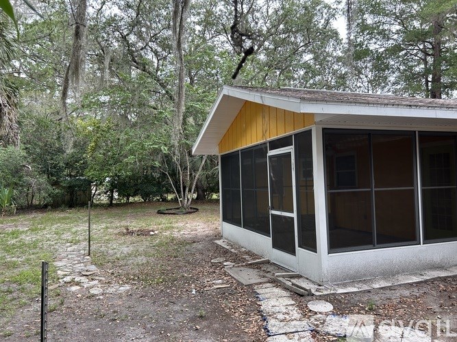A small house with a yellow roof is surrounded by trees.