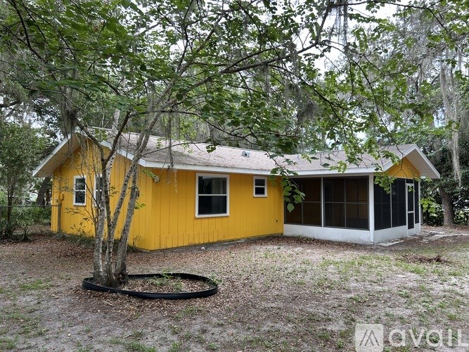 A yellow house with a tree in front of it.