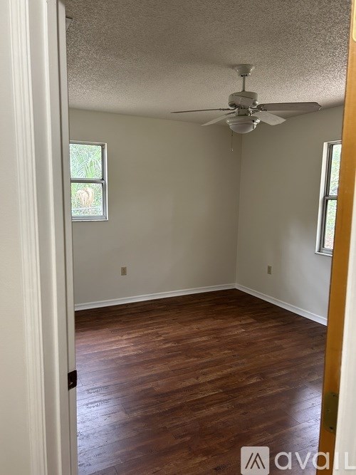 A room with a ceiling fan and wooden flooring.