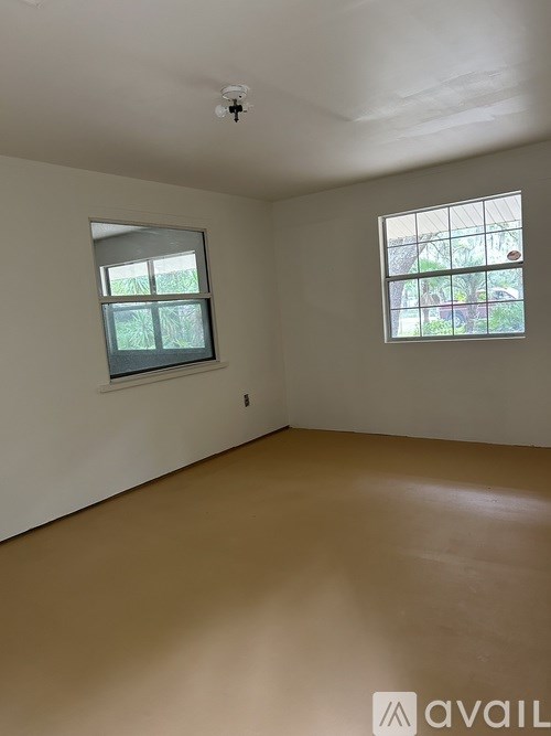 A room with a window and a smoke detector on the ceiling.