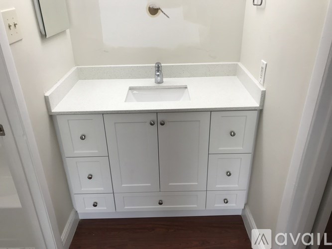 A white bathroom vanity with a sink and a mirror above it.