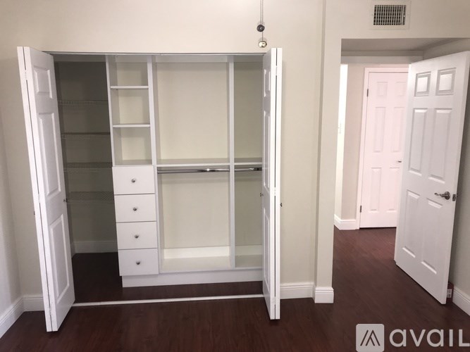 A white wardrobe with glass doors and drawers is in a room with a white door.