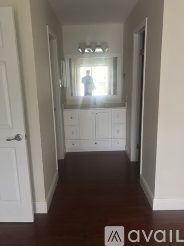 A hallway with a white door and a mirror on the wall.