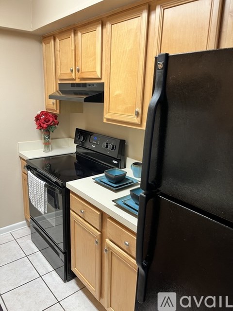 A kitchen with wooden cabinets and a black refrigerator.