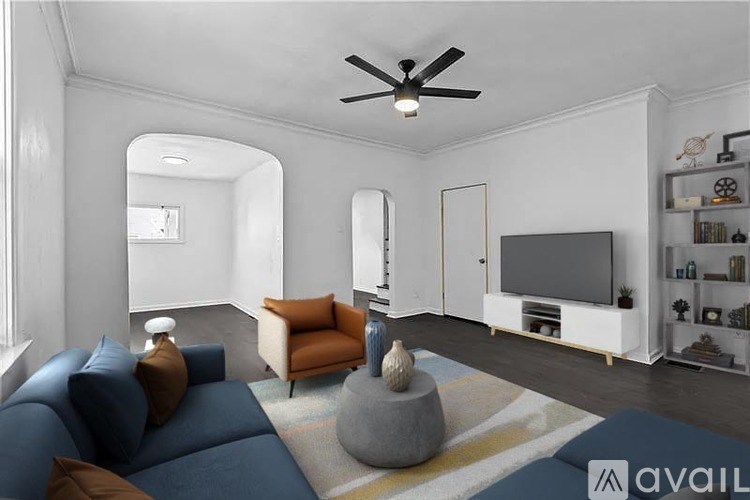 A living room with a blue couch, a grey stone table, and a white ceiling fan.