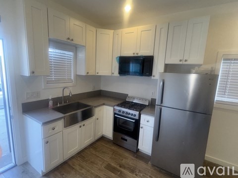 A kitchen with white cabinets and a stainless steel refrigerator.