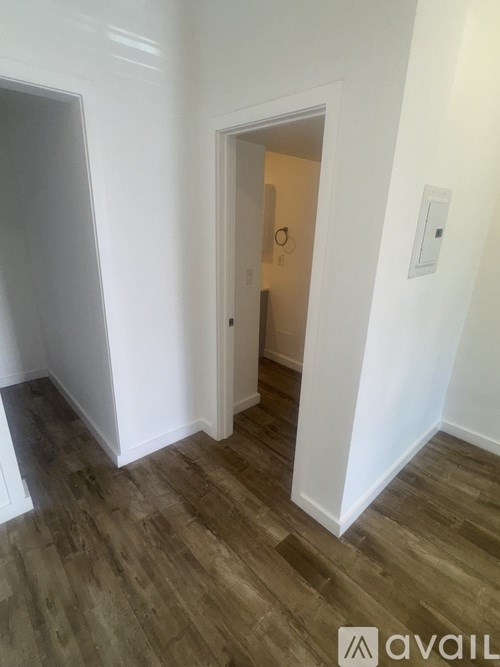 A hallway with a door and a light switch on the wall.