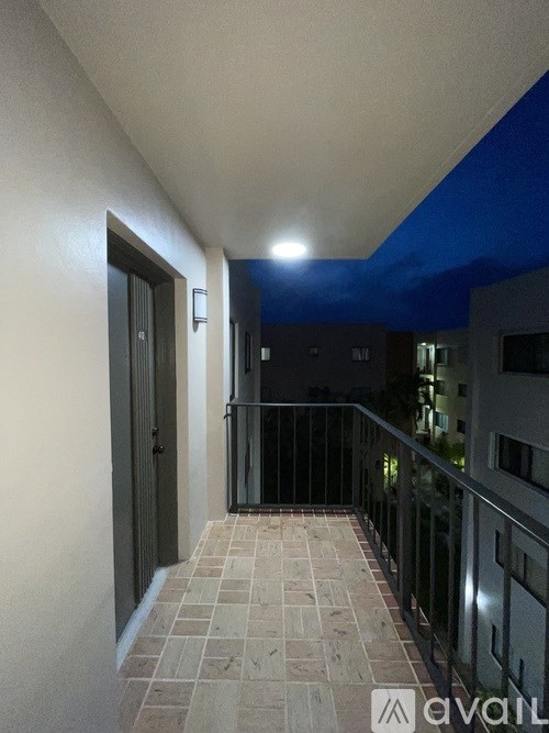 A hallway with a tiled floor and a balcony with a metal railing.