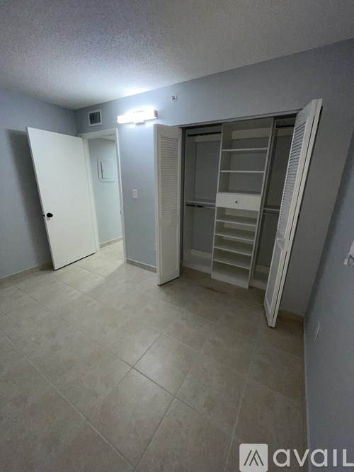 A room with a white door, a white cabinet, and a white refrigerator.