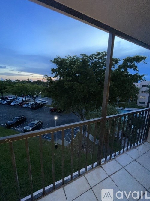 A balcony view of a parking lot with cars and trees.