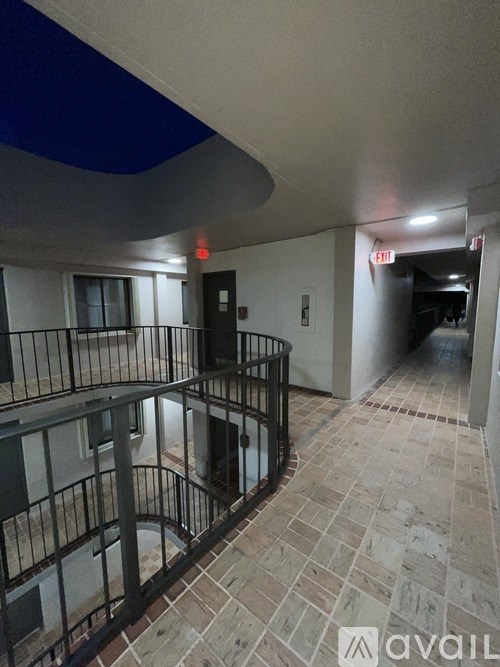 A hallway with a blue and white wall and a black railing.